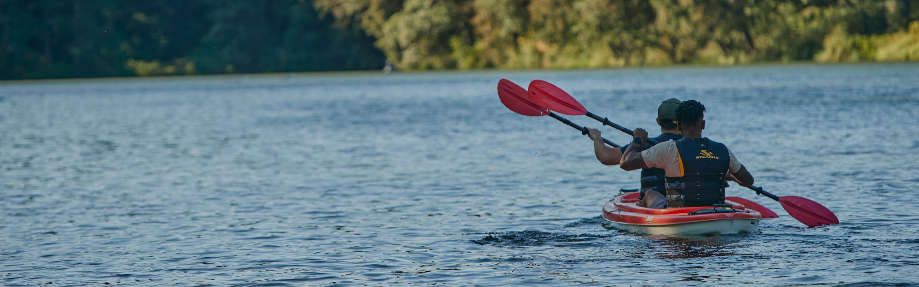 two people paddling down river wearing life vests