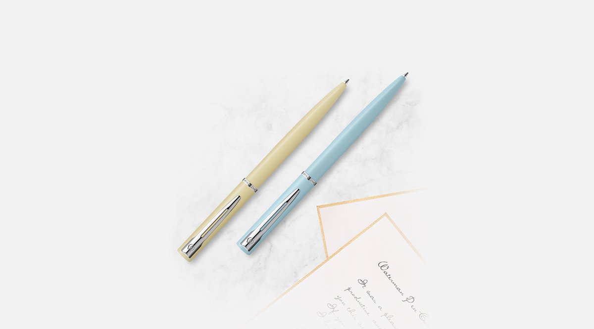 Two Allure ballpoint pens in pastel finishes laid next to a written note card.