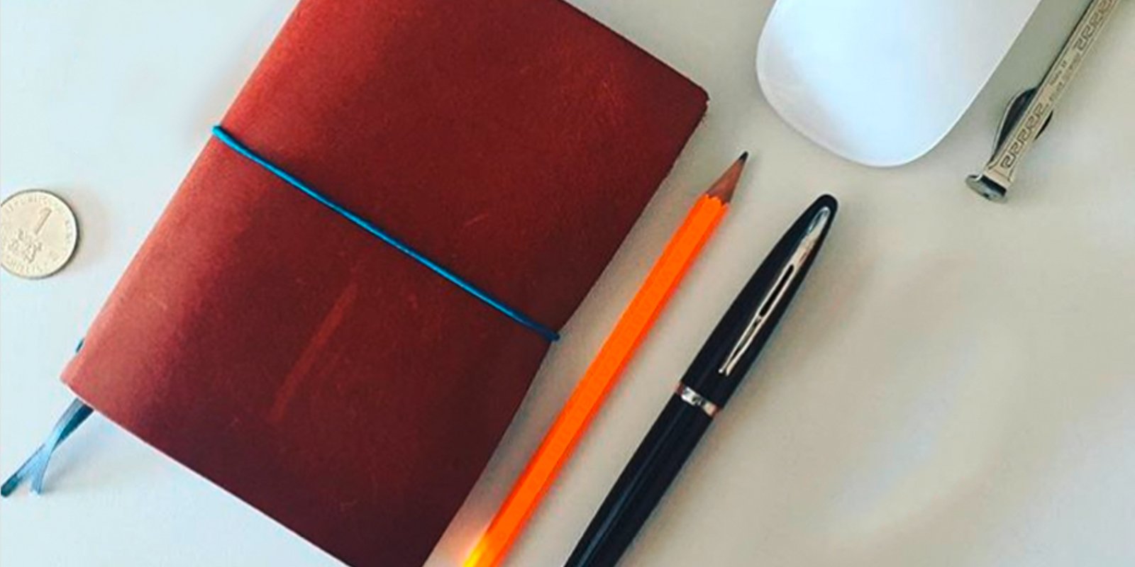 A capped Carene pen on a desk with a pencil, journal and cup of coffee.