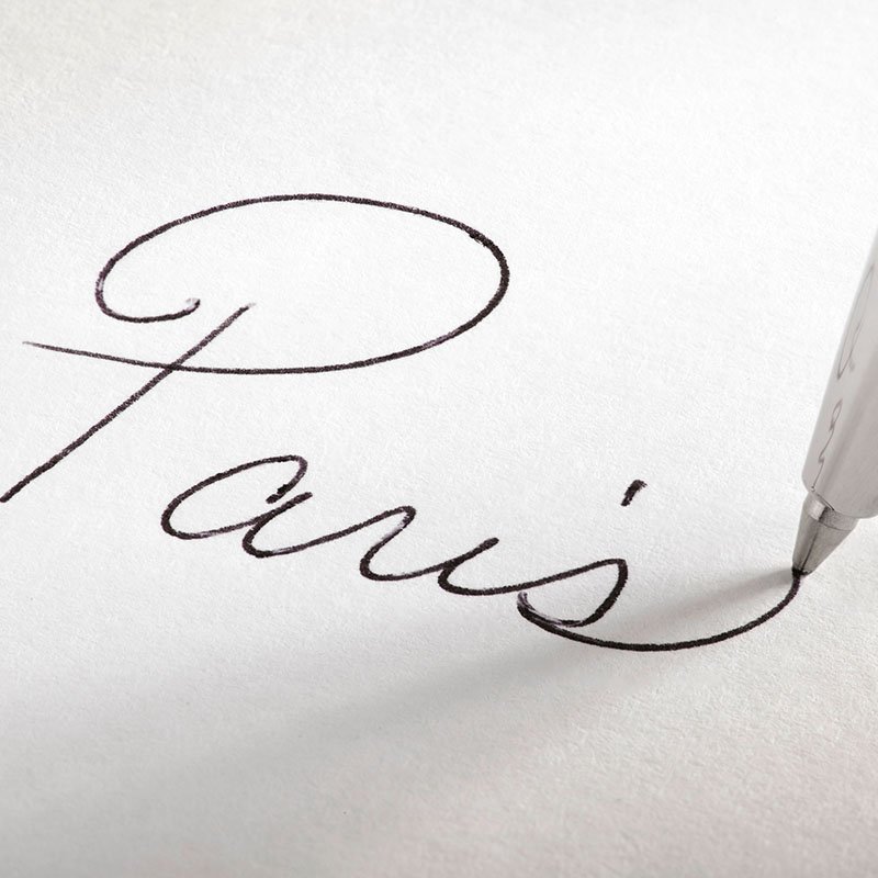 Closeup of a pen writing the word Paris.