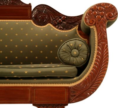 Regal upholstery on an Empire-style sofa, with round bolster pillows on either end.