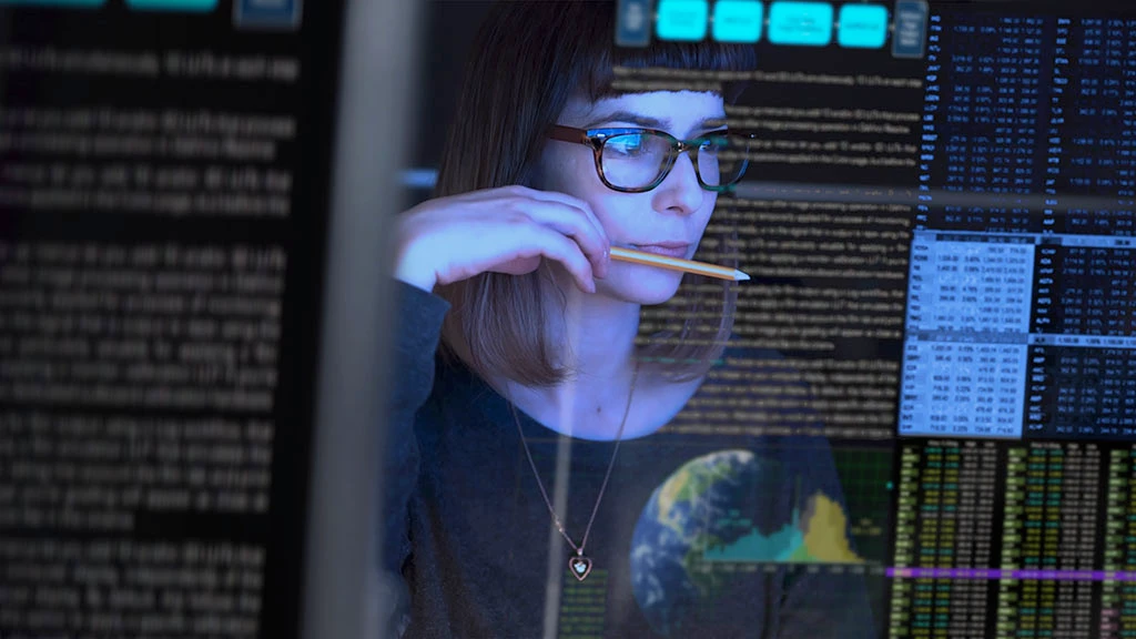 Stock image of a beautiful young woman studying a see through computer screen & contemplating.