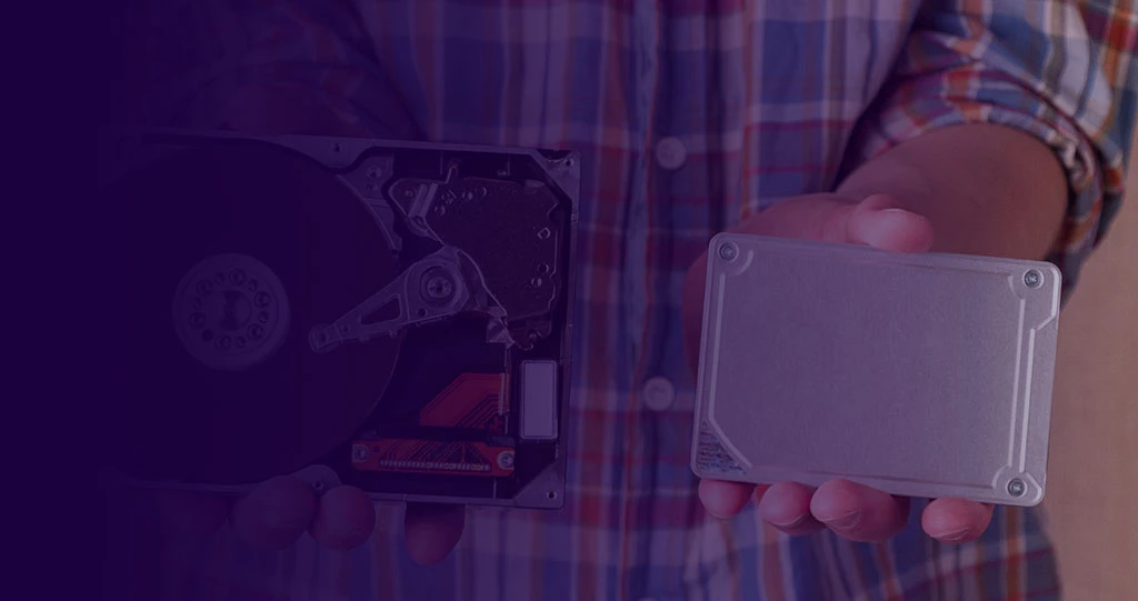 Man holding a large hard disk drive vs an SSD that is smaller and has no moving parts