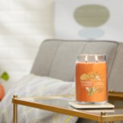 honey clementine signature large jar candle lit on side table with coaster image number 3