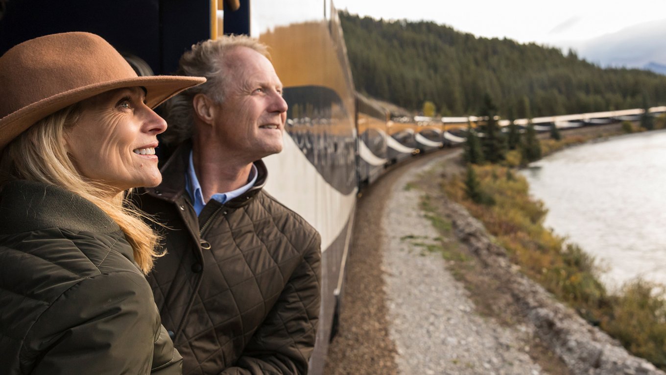 Couple on Train looking out at forest and lake scenery