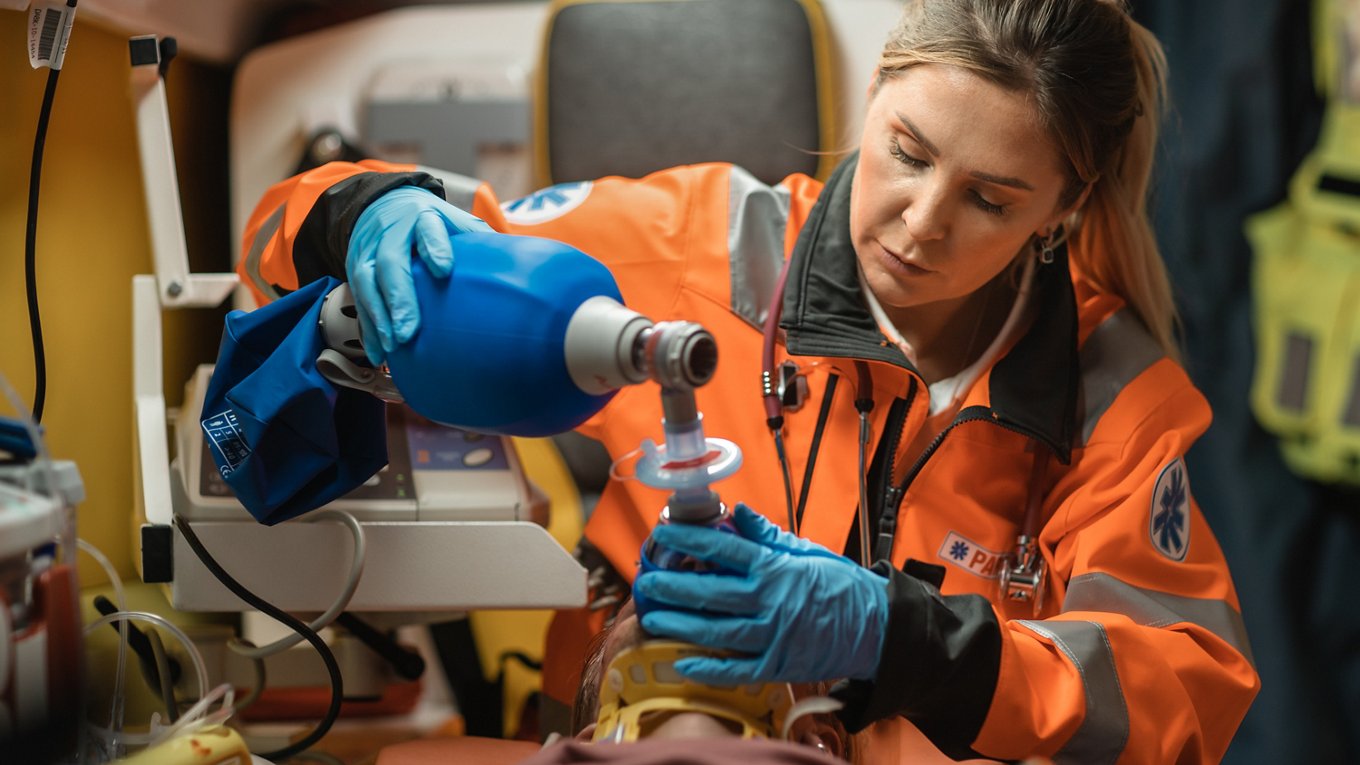 Paramedic using resuscitation equipment in ambulance 