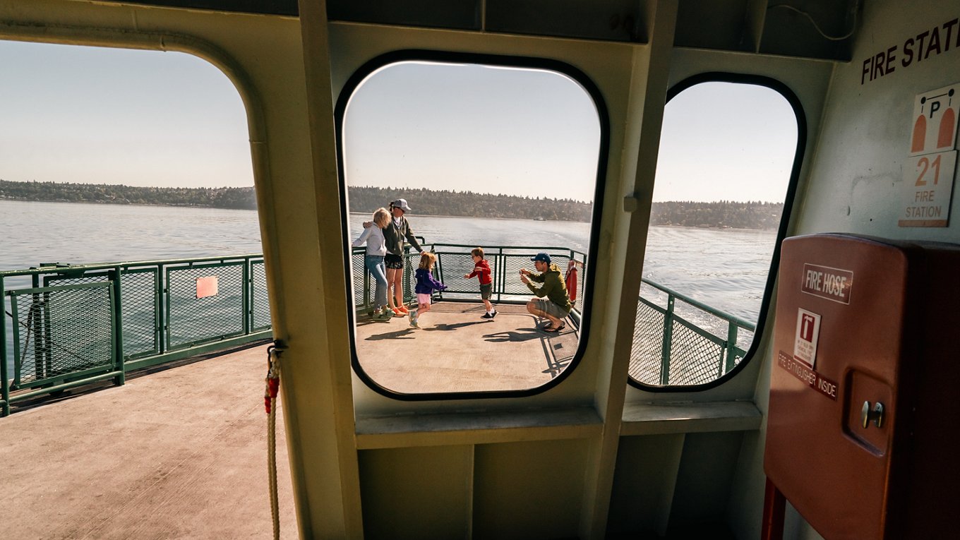 Family on ferry deck taking photos on sunny day