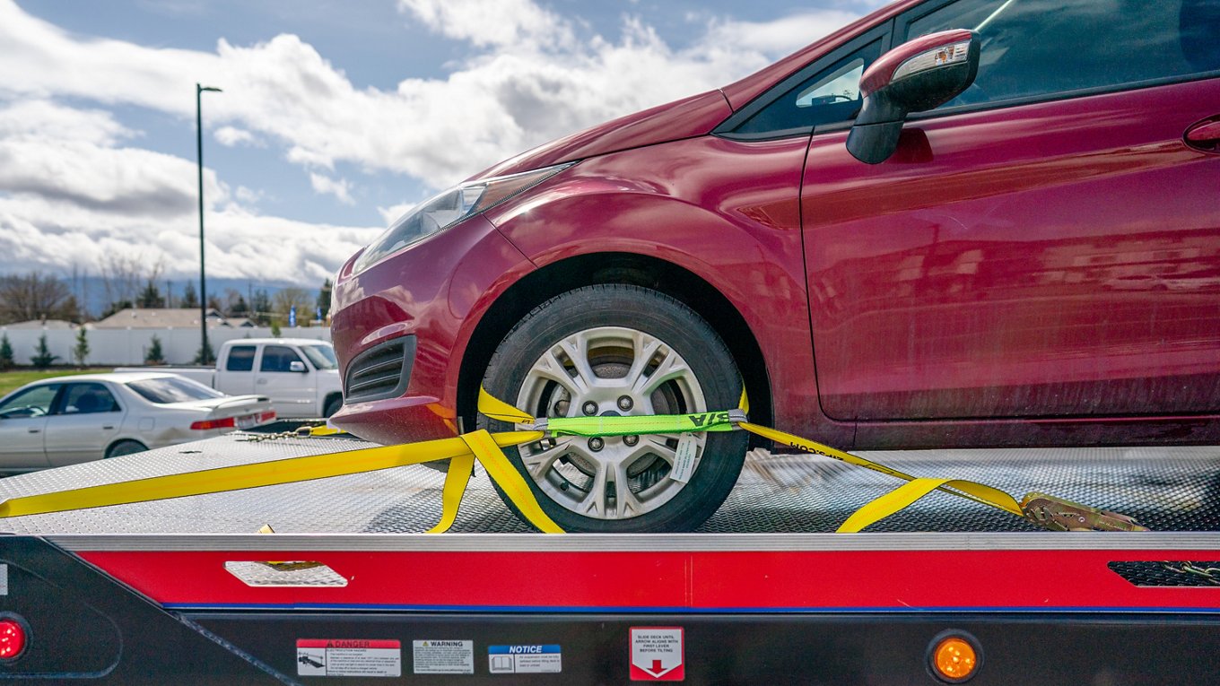red vehicle strapped on a tow truck