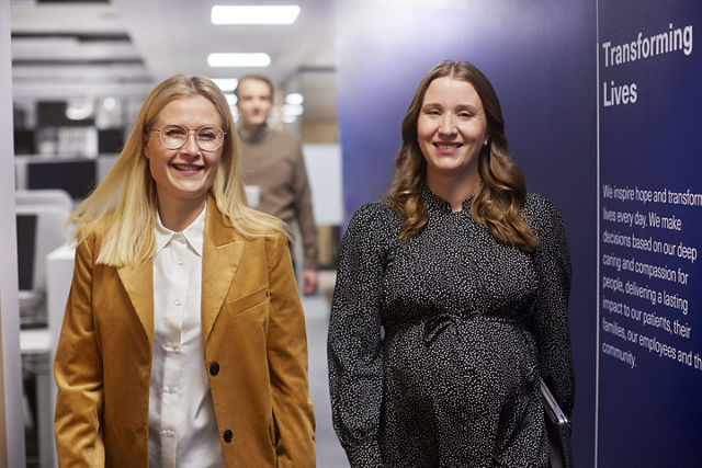 Two female employees walking the halls in an office wearing business attire