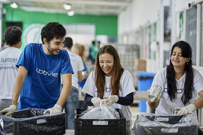 employess smiling while working side-by-side at a volunteering event. 