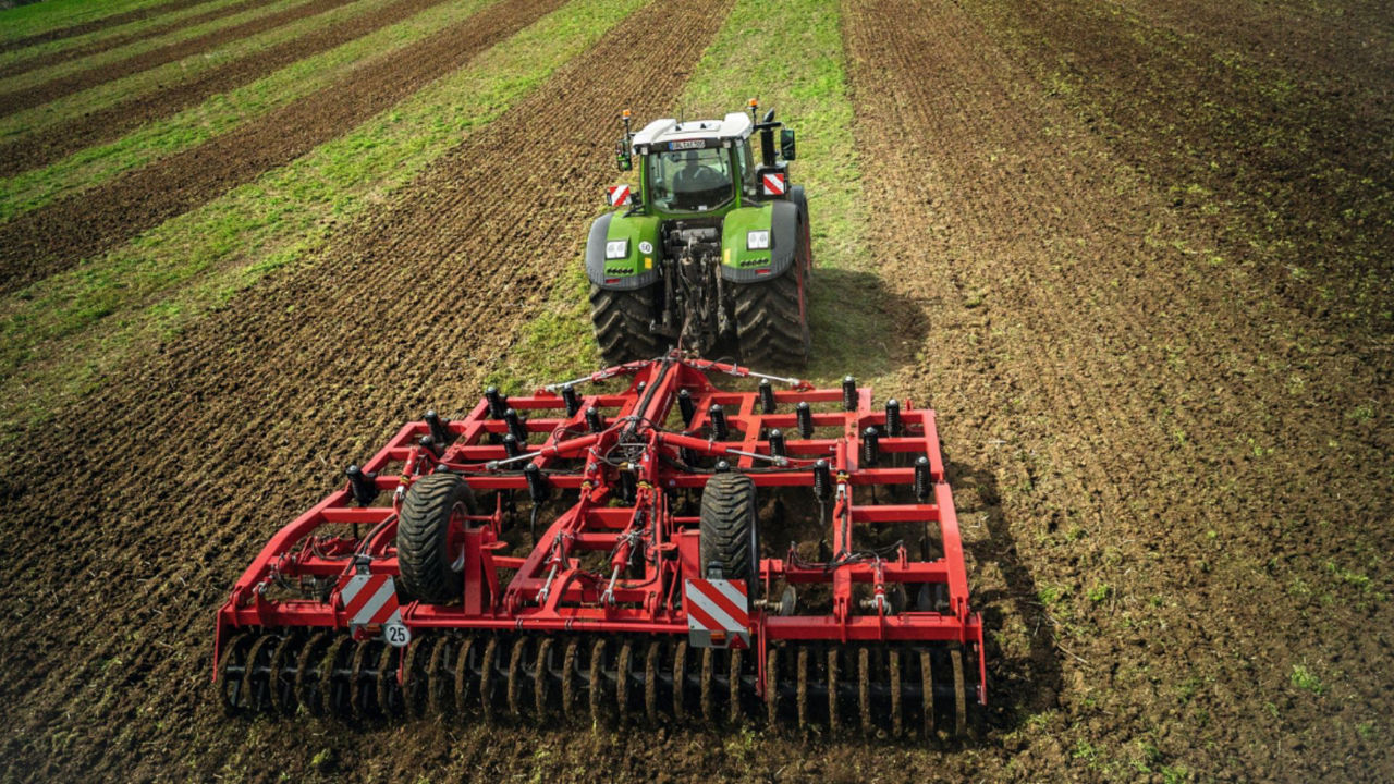 Farmer uses tractor to disc a field