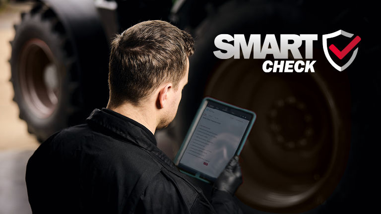 A technician examining an iPad in front of a tractor 