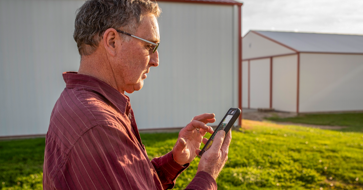 A man looks at FarmENGAGE on a cell phone