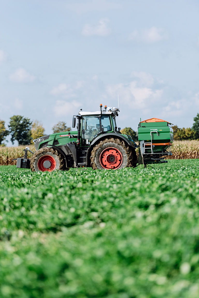 Fendt tractor applying crop treatment in a green agricultural field.