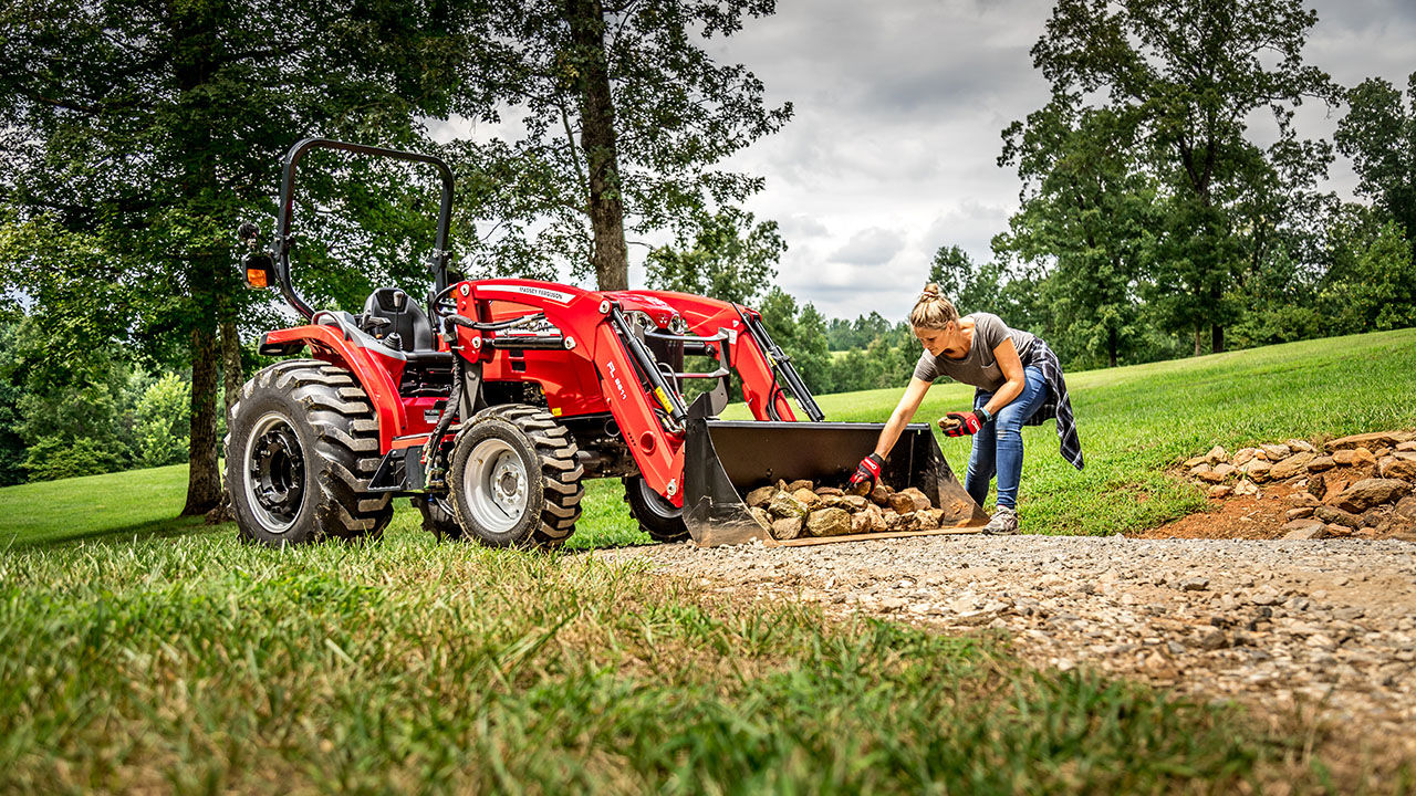 woman loading rocks into a Massey ferguson 1800M series tractor