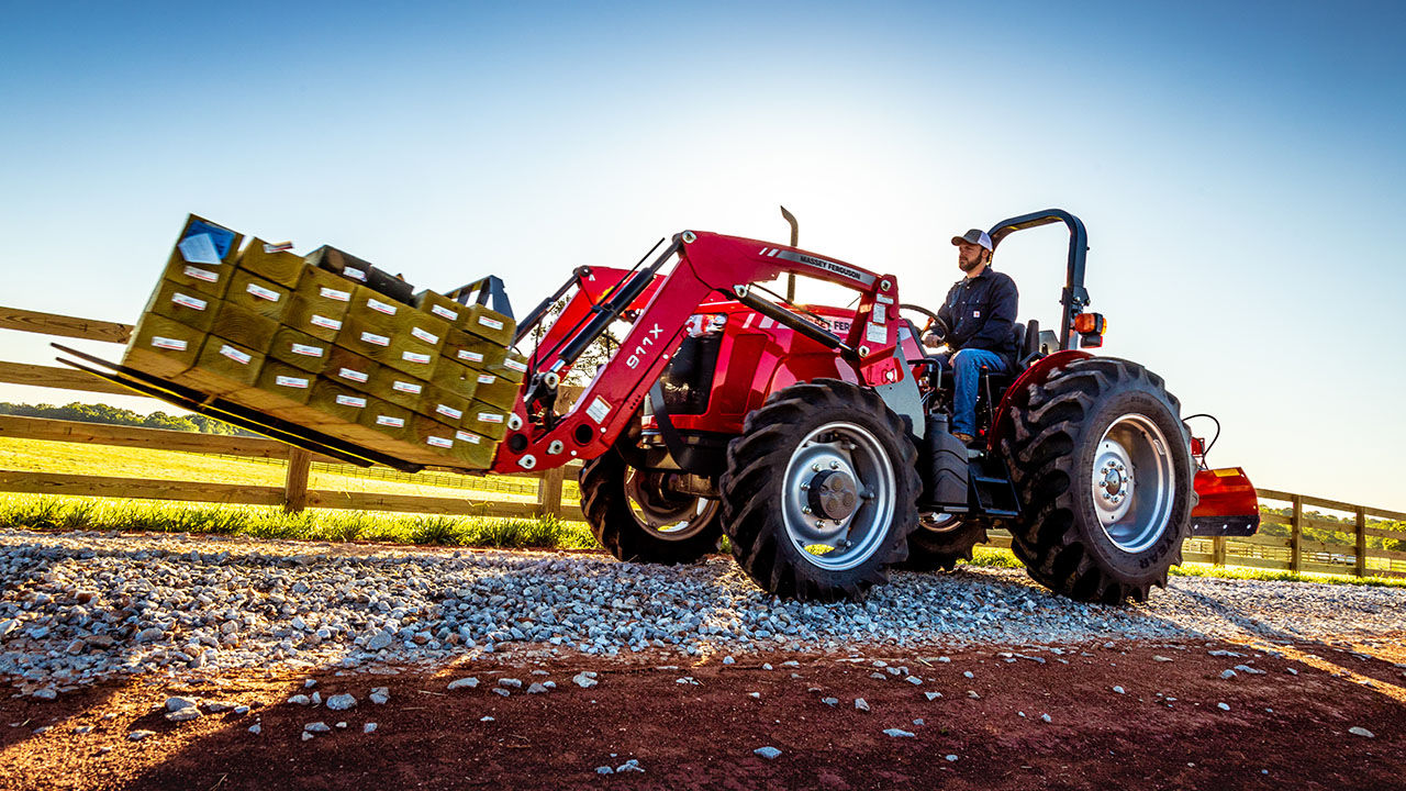 man hauling lumber with a Massey ferguson 2600H series tractor