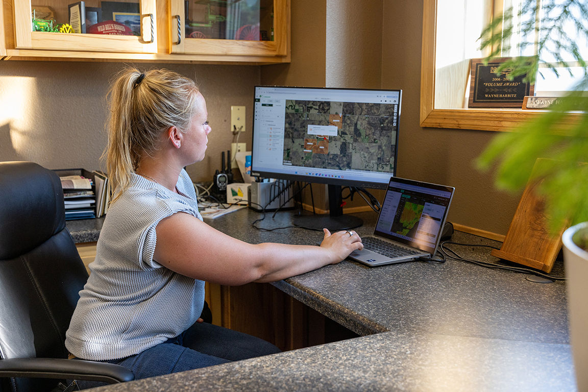 User working with digital farm management and mapping software on computer screens.