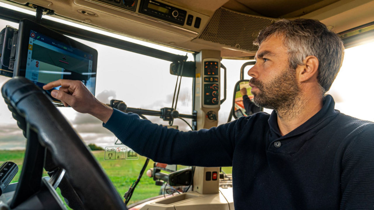 Man in tractor cab using display screen