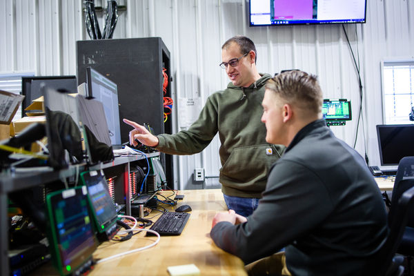 Two PTx employees look at a computer screen.