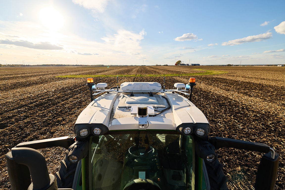 View of a tractor equipped with autonomous farming technology operating in a cultivated field.