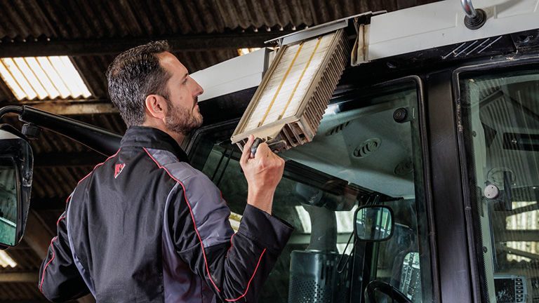 Tre tekniker arbetar på olika delar av en traktor