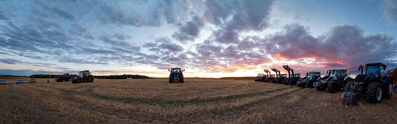 A lineup of Valtra tractors at a SmartTour evening event at sunset