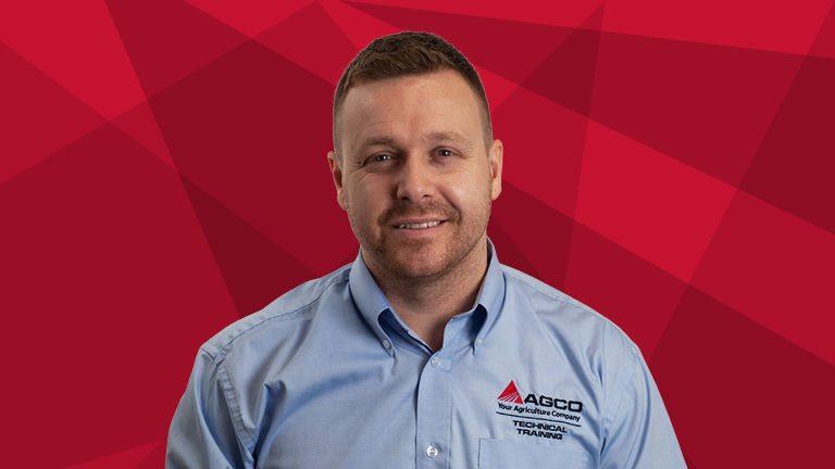 A headshot of Ashley Briggs on a red background