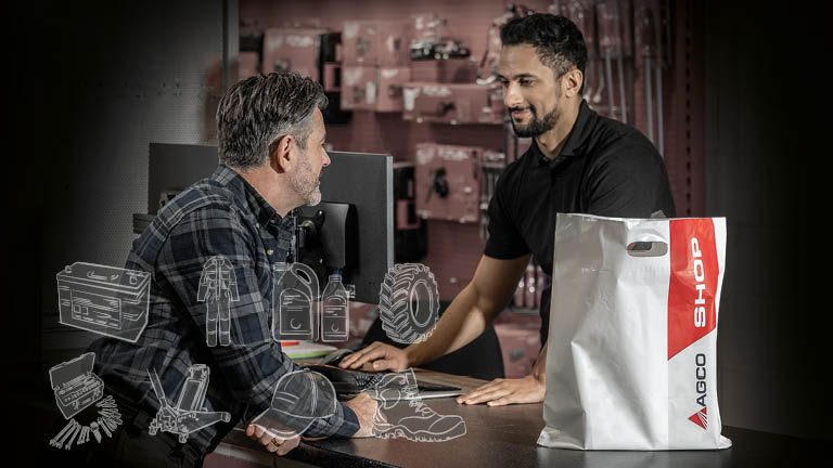 A man buying products from a dealer with a  AGCO Shop carrier bag on a counter