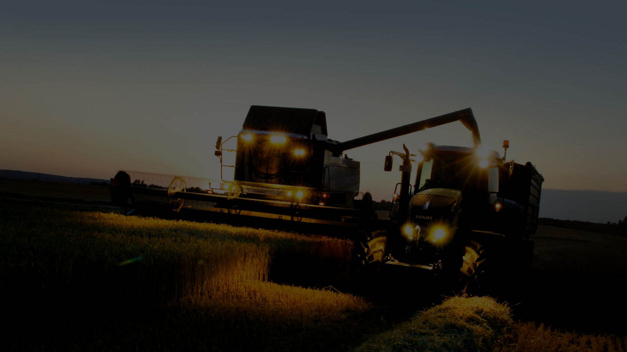 A combine and a tractor in a field harvesting crops