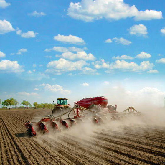 Red tractor in a field at sunset.