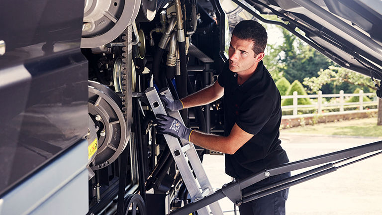 A male technician examining a combine harvester engine