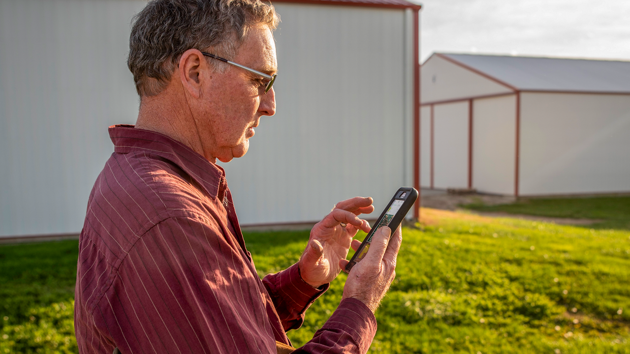 A man uses PTx FarmENGAGE on a cell phone