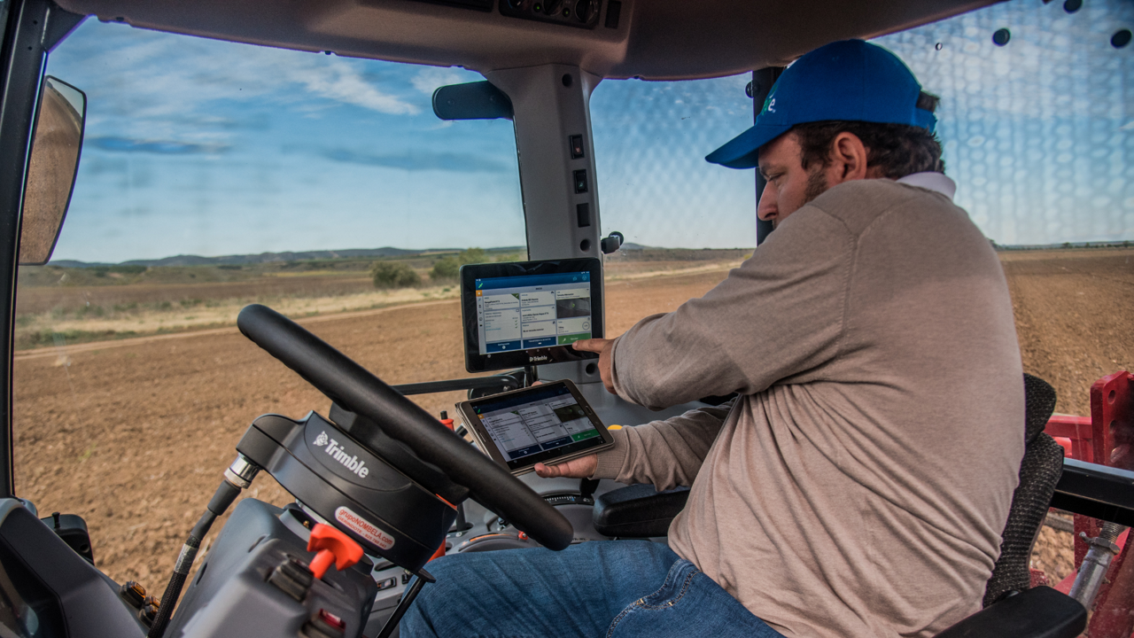 A farmer drives a tractor without hands using PTx Trimble autoguidance.