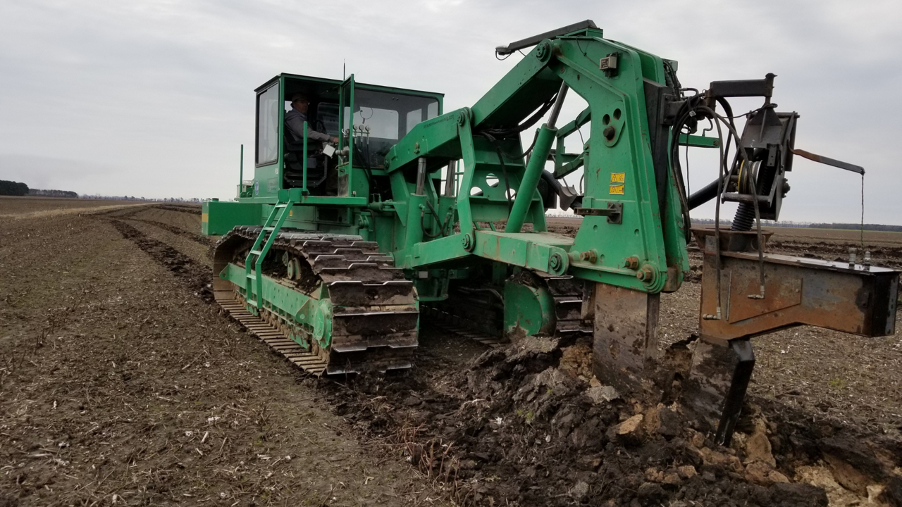 A tile plow works through a field