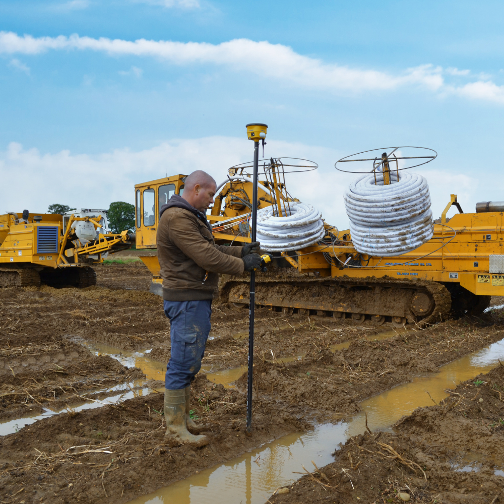 A man surveys a field before installing drainage