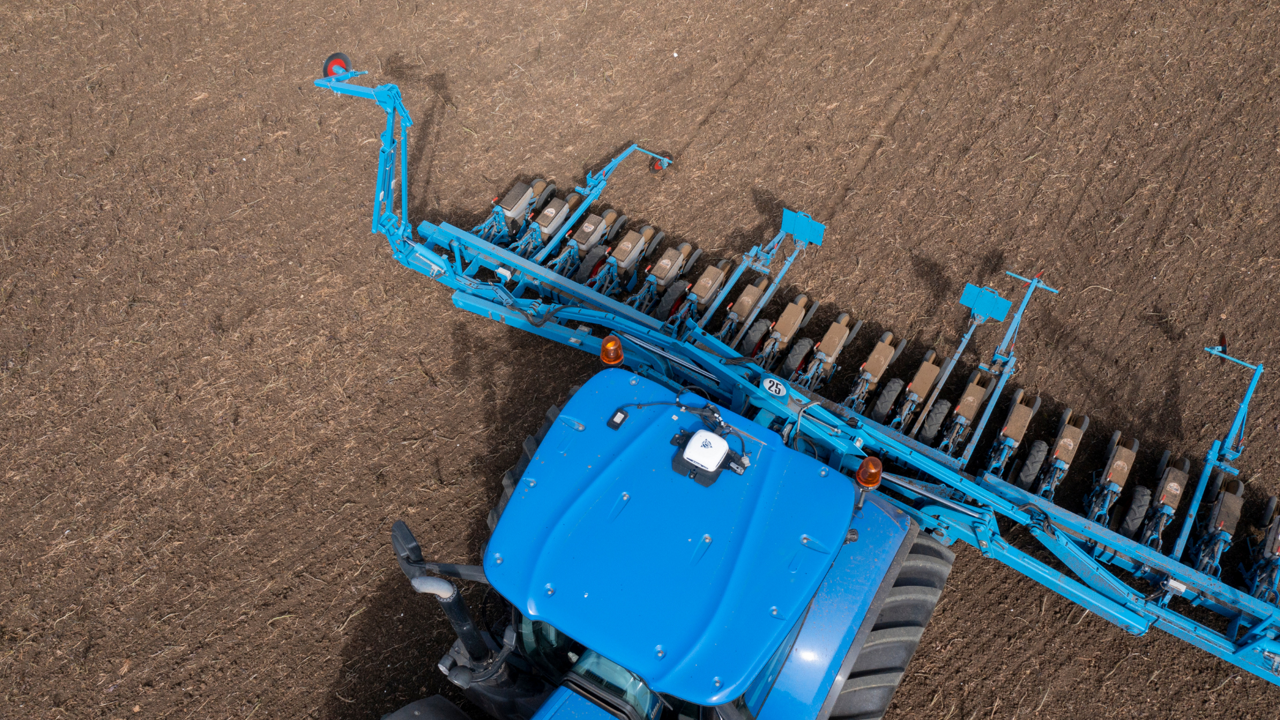 An overhead view of a blue tractor and planter with the NAV-900 guidance controller.