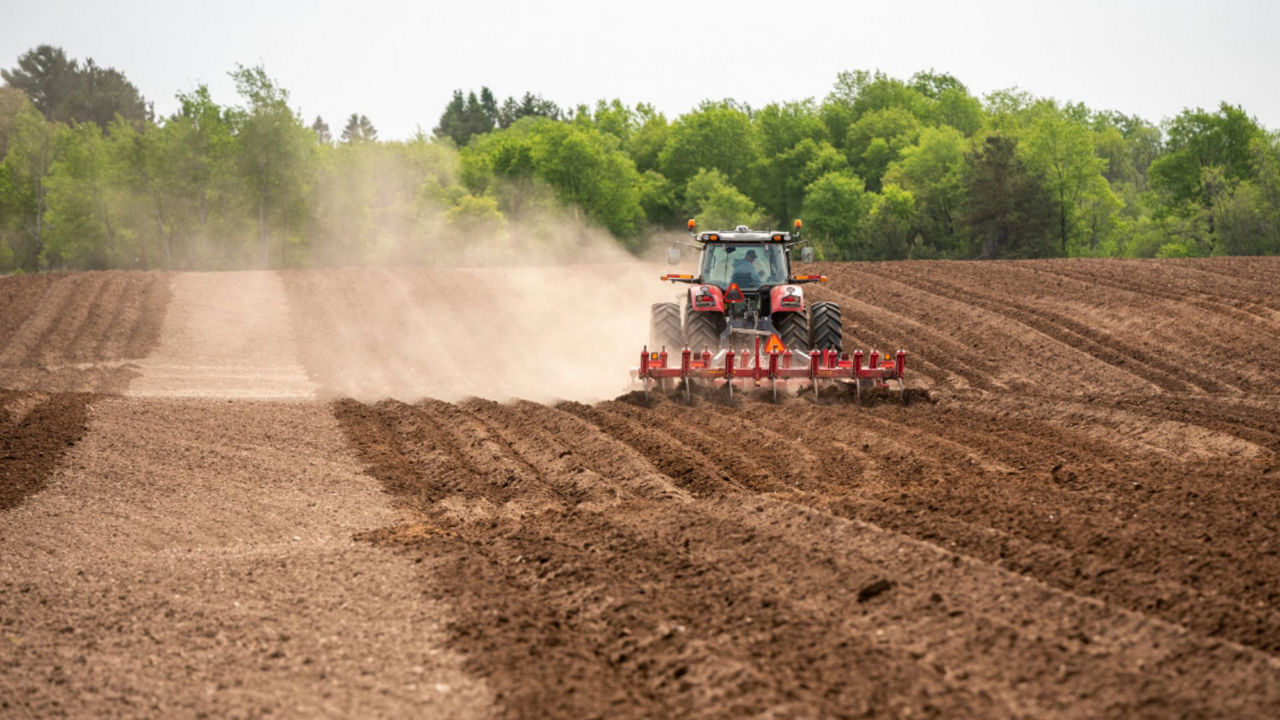 An aerial shot of a tractor driving in straight lines.