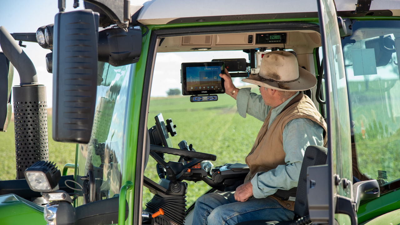 Farmer using a PTx Trimble GFX precision agriculture display in a tractor cab
