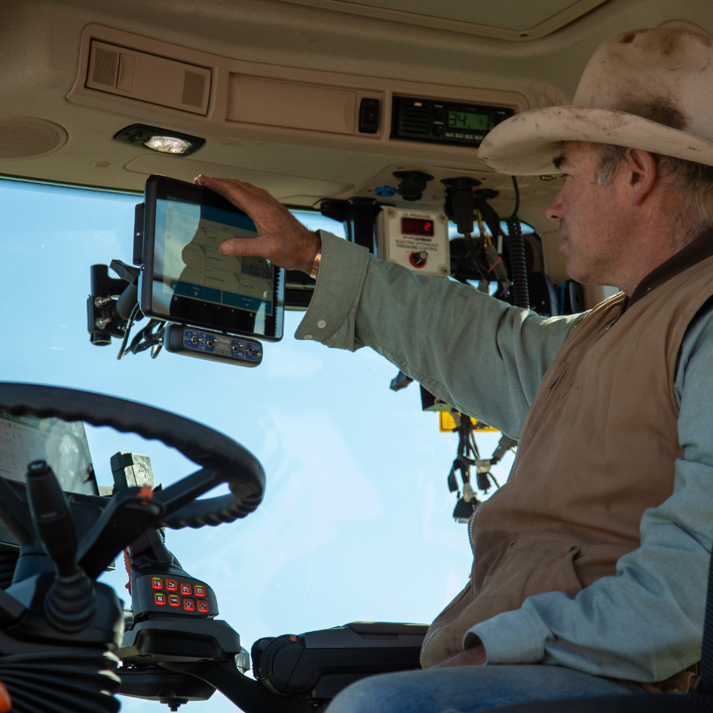 Man in tractor cab using display screen