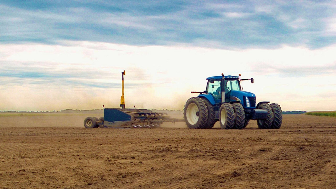 A tractor levels a field using PTx Trimble technology.