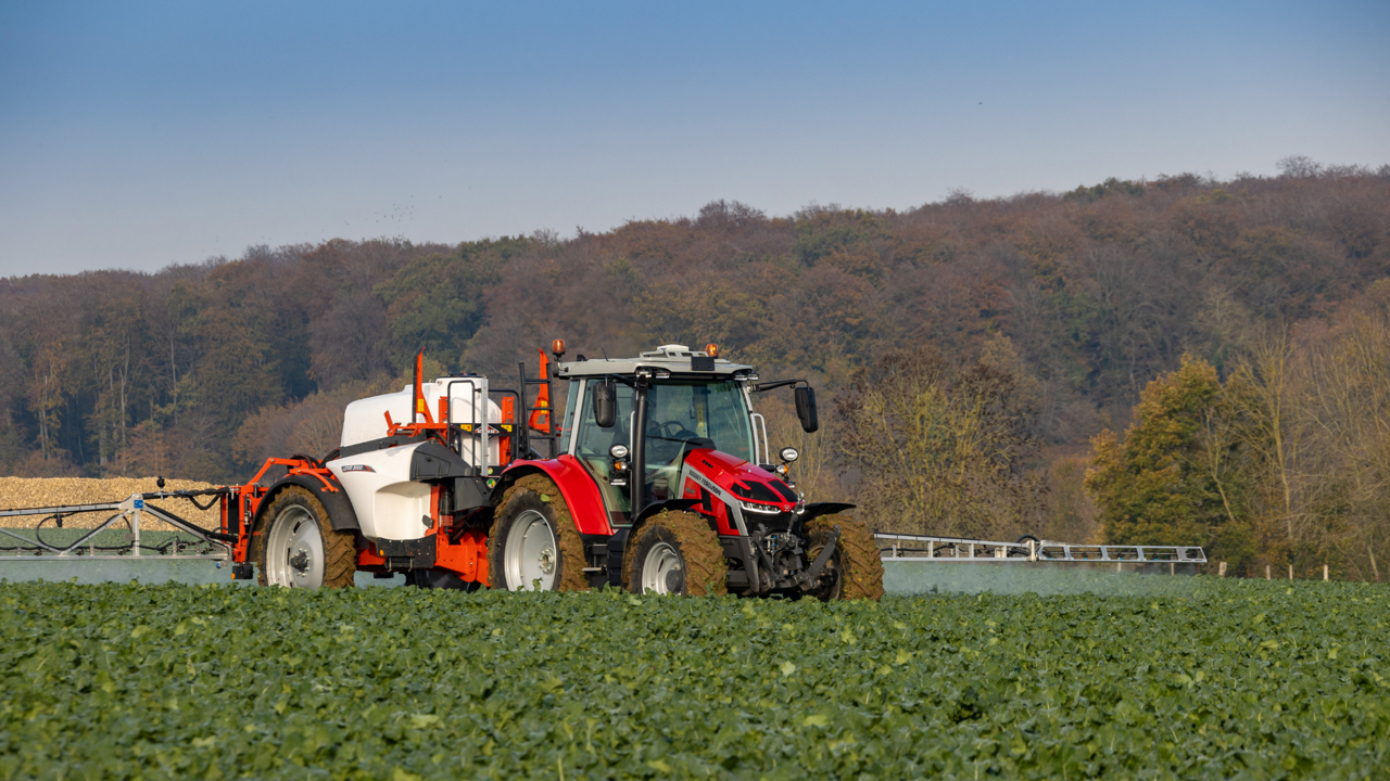 A red tractor and sprayer in the field.