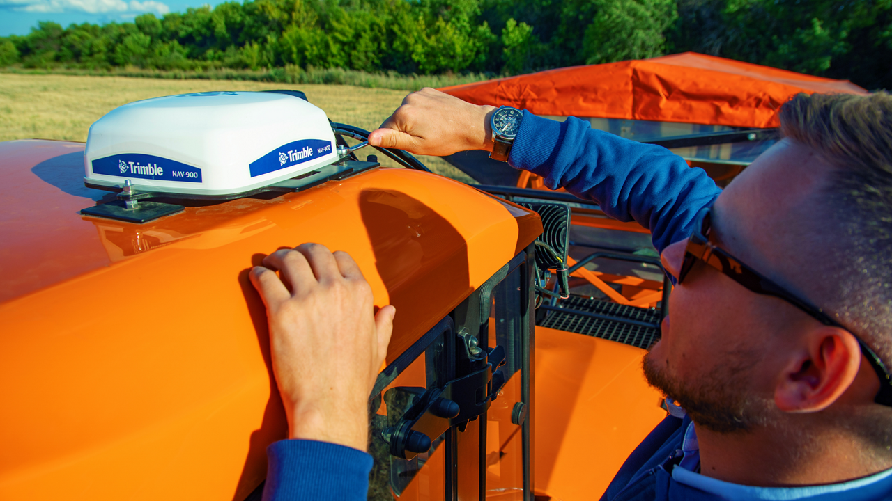 A man installs the PTx Trimble NAV-900 receiver on the roof of a tractor.