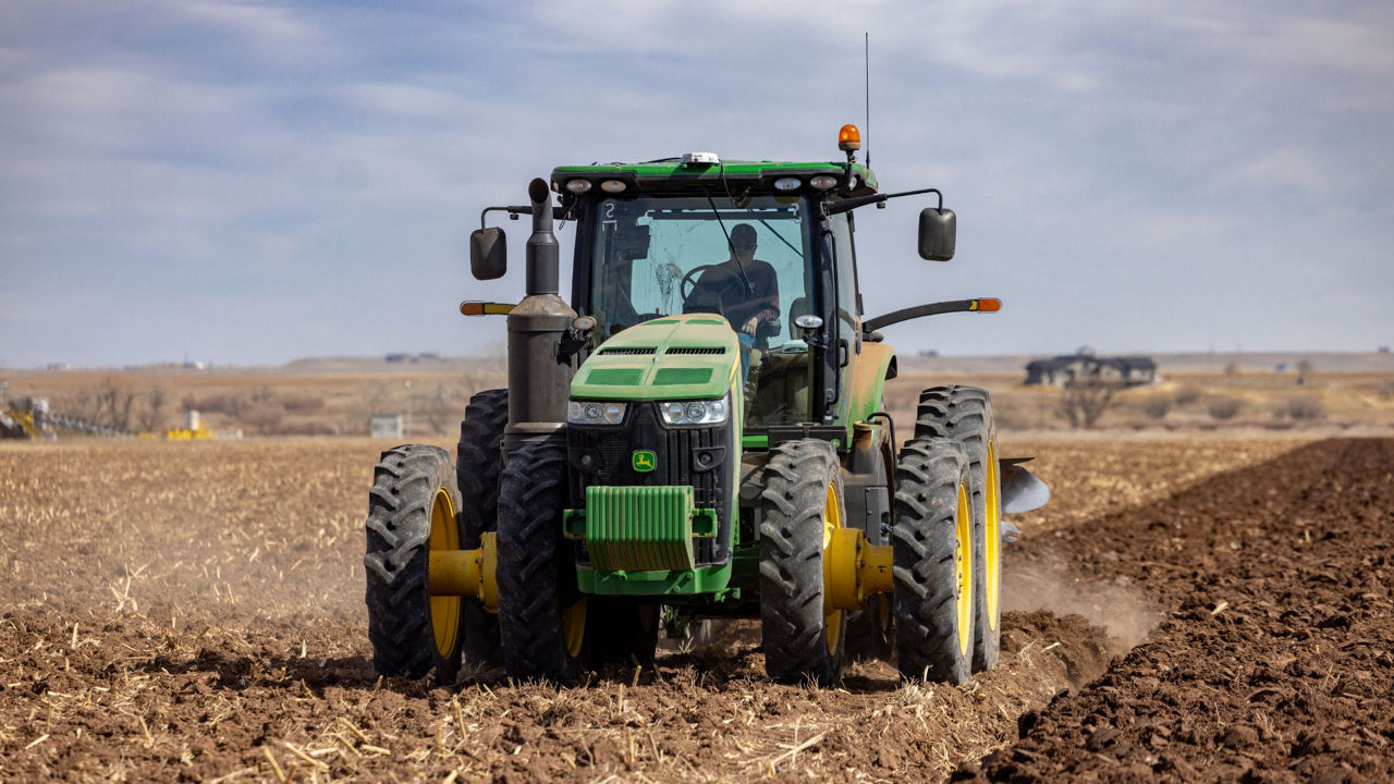 A red tractor works a field using the PTx Trimble EZ-Steer system.