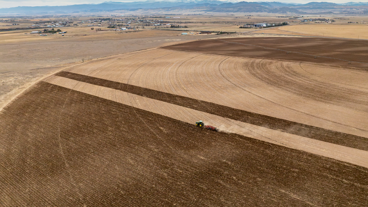 An aerial shot of a tractor driving in straight lines.