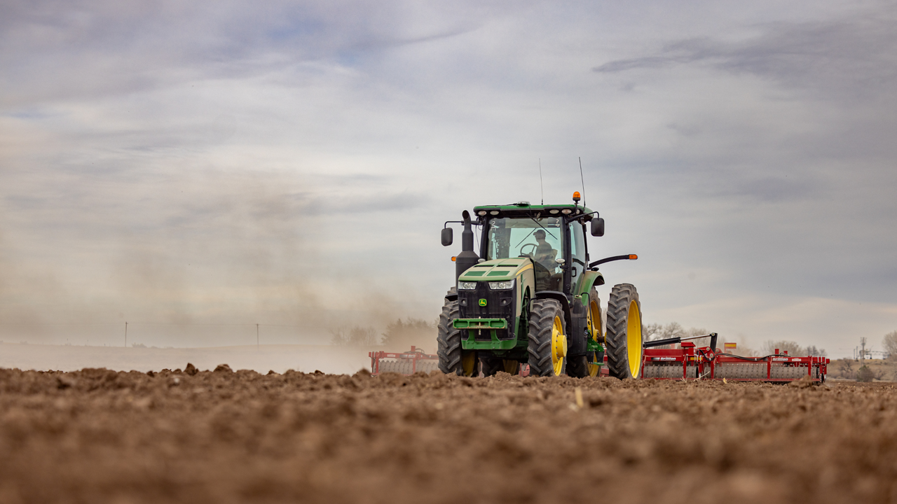 A farmer works a dusty field.