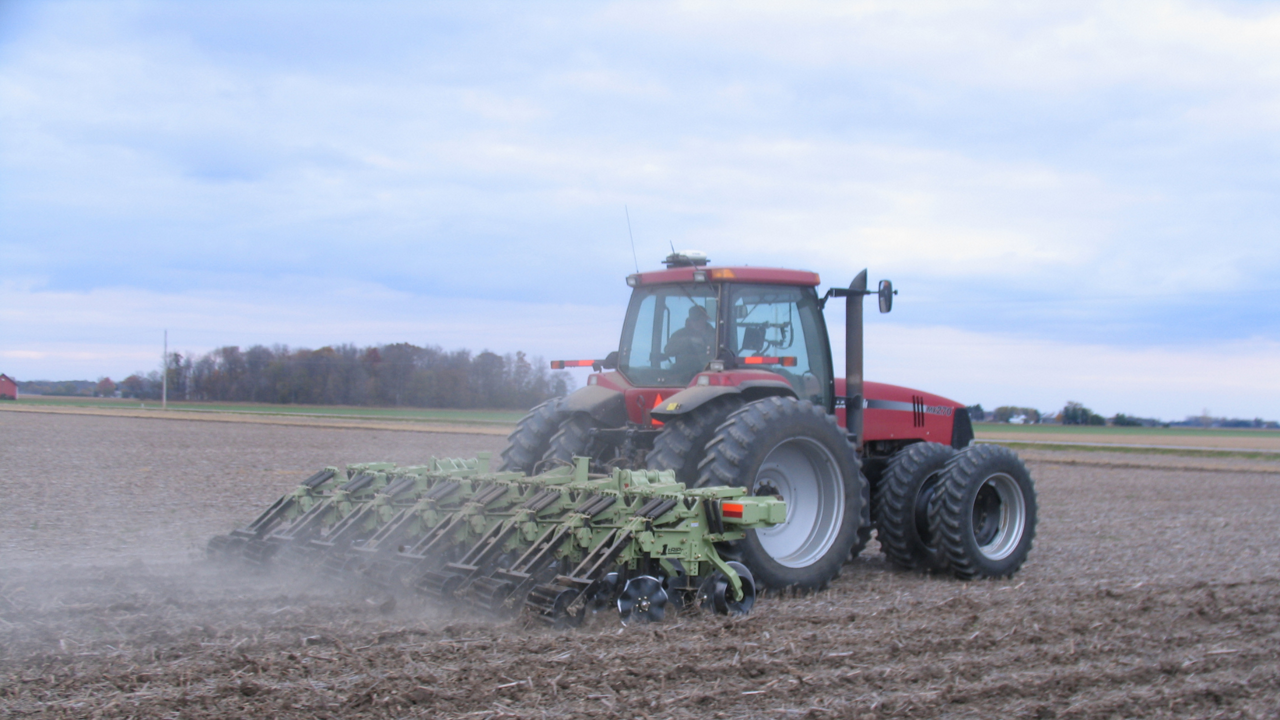 A red tractor works a field.