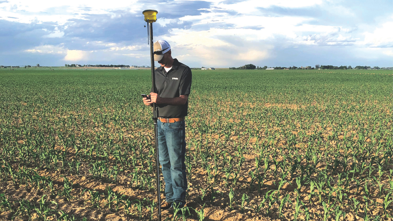 A man uses PTx Trimble's WM-Survey II app to survey a field