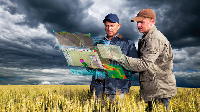 Two farmers in a field looking at an iPad with holographic screens superimposed