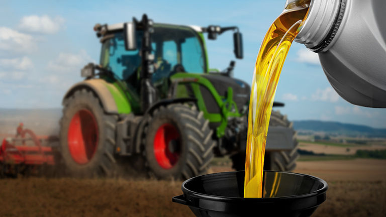 A picture of a lubricant being poured into a funnel superimposed onto a tractor in a field