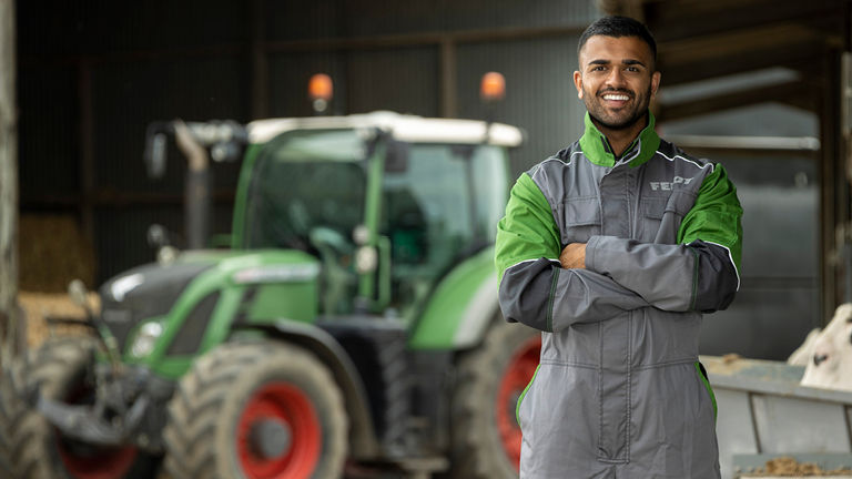 Farmer standing near green tractor in barn